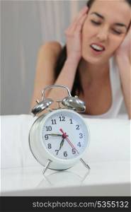 Unhappy woman shutting out the noise of her alarm clock