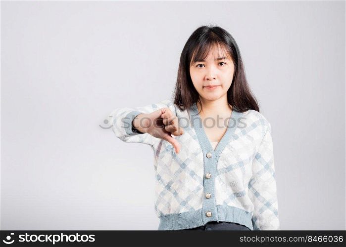Unhappy woman smile show finger thumbs down rejection unlike, Portrait Asian beautiful young female negative gesture showing finger thumbs down or dislike sign studio shot isolated on white background