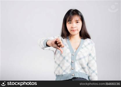 Unhappy woman smile show finger thumbs down rejection unlike, Portrait Asian beautiful young female negative gesture showing finger thumbs down or dislike sign studio shot isolated on white background