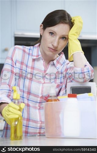 Unhappy Woman Surrounded By Cleaning Products At Home