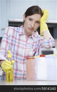 Unhappy Woman Surrounded By Cleaning Products At Home