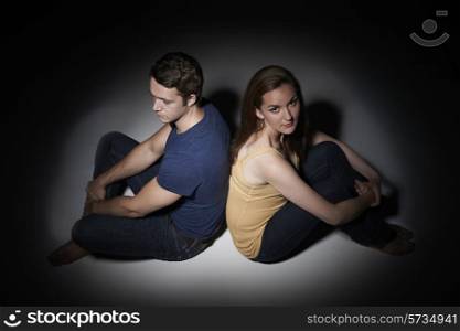Unhappy Young Couple Sitting In Pool Of Light