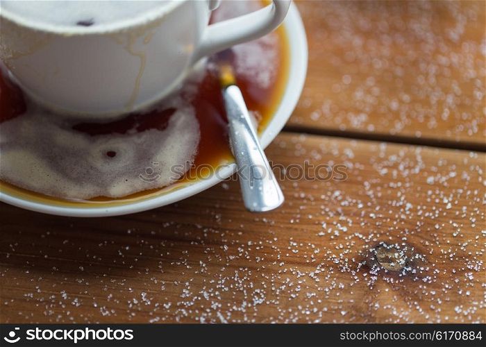 unhealthy eating, object and drinks concept - close up coffee cup and sugar poured on wooden table
