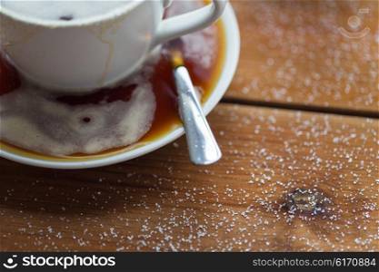 unhealthy eating, object and drinks concept - close up coffee cup and sugar poured on wooden table