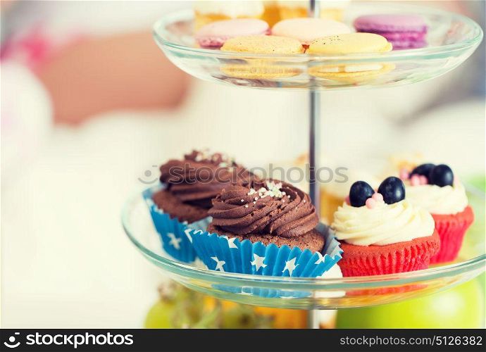unhealthy eating, sweets, dessert, baking and junk food concept - close up of cake stand with cupcakes and cookies. close up of cake stand with cupcakes and cookies