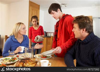 Unhelpful Teenage Clearing Up After Family Meal In Kitchen