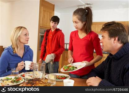 Unhelpful Teenage Clearing Up After Family Meal In Kitchen