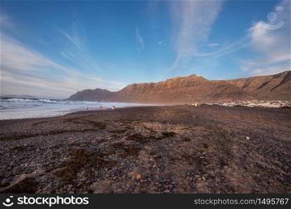 Unidentifiable surfers in famous Famara beach in Lanzarote, Canary islands, Spain.