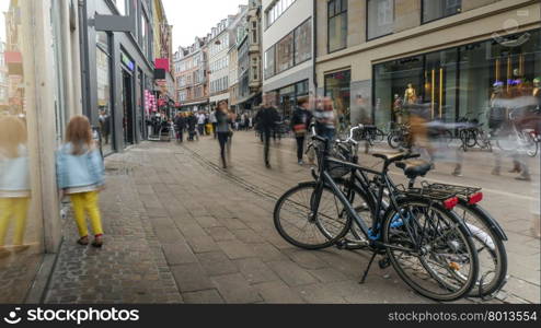 Unidentified child in yellow pants walking along busy street with parked bicycles in Copenhagen. Child walks along street in Copenhagen