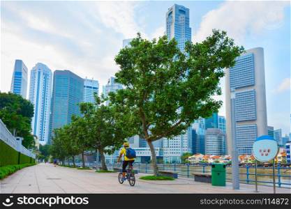 Unidentified man riding bicycle on Singapore river embankment