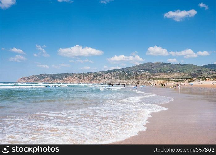 Unidentified people with surf board on summer beach and blue ocean water. Summer beach panoramic view