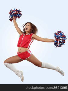 Uniformed cheerleader jumps high in the air isolated on white.