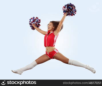 Uniformed cheerleader jumps high in the air isolated on white.