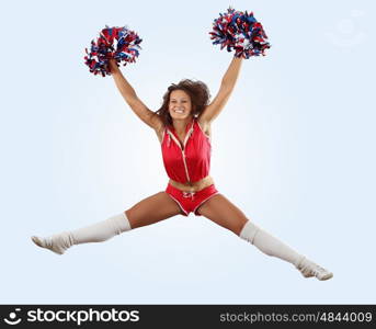 Uniformed cheerleader jumps high in the air isolated on white.