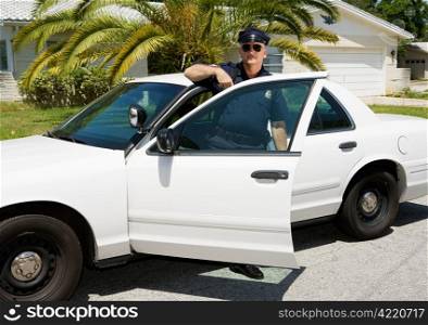 Uniformed law enforcement officer standing in the door of his police car.