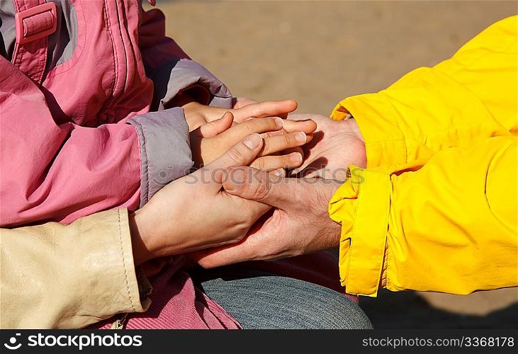 United hands of adults and child as symbol of family unity. Photo outdoors.