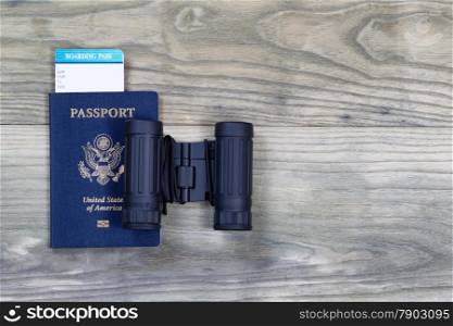 United States passport, boarding pass and binoculars on faded wooden boards.