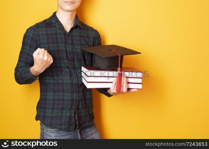 University man is happy with graduation on yellow background