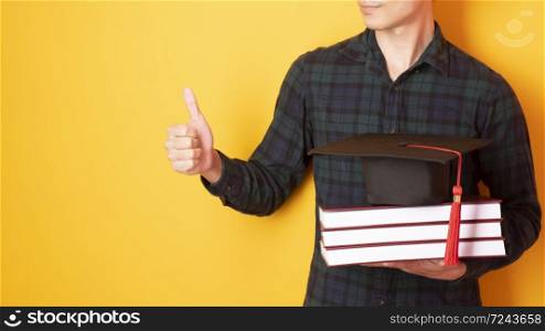 University man is happy with graduation on yellow background