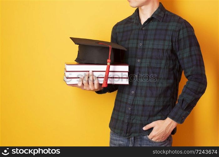 University man is happy with graduation on yellow background