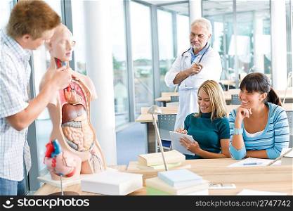 University - medical students with professor and human anatomical model in classroom