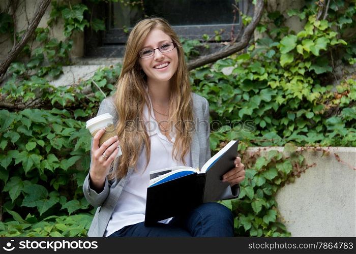 University student reading a book and enjoying a beverage