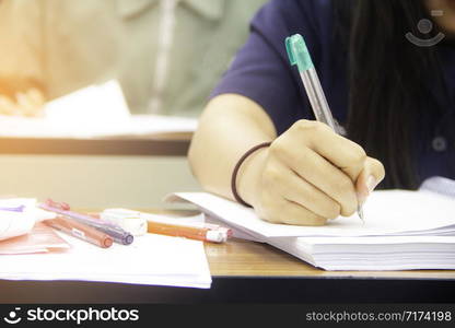 University students do quiz, test or studies from the teacher in a large lecture room. Students in uniform attending exam classroom educational school.