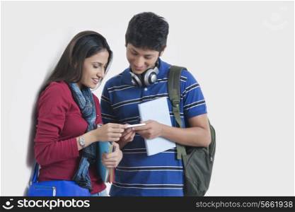 University students using smart phone against wall
