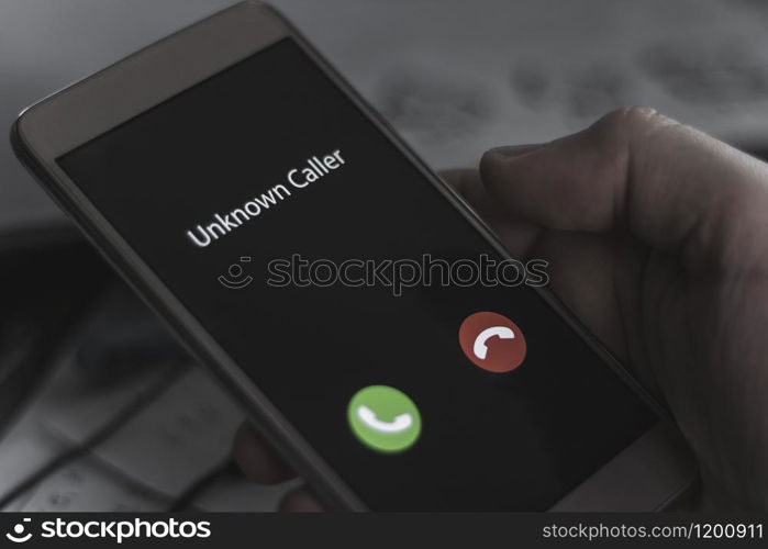 Unknown caller. A man holds a phone in his hand and thinks to end the call. Incoming from an unknown number at night. Incognito or anonymous