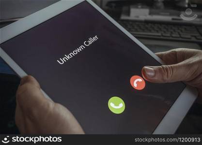 Unknown caller. A man holds a tablet in his hand and thinks to end the call. Incoming from an unknown number at night. Incognito or anonymous