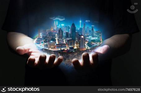 Unknown hand holding fantasy island floating in the air with modern city skyline , Night scene .