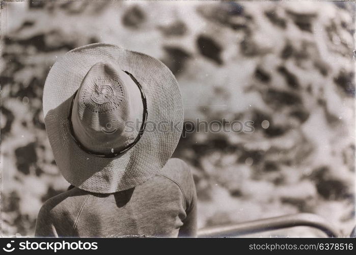 unknown woman with hat looking at the ocean like vacation concept