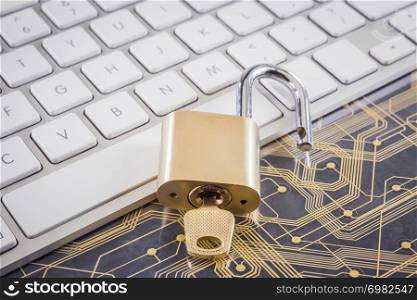 Unlock gold metal padlock with key on modern white keyboard, plastic electronic circuit board on background. Digital data, encryption, online password, cyber security, information privacy concepts.