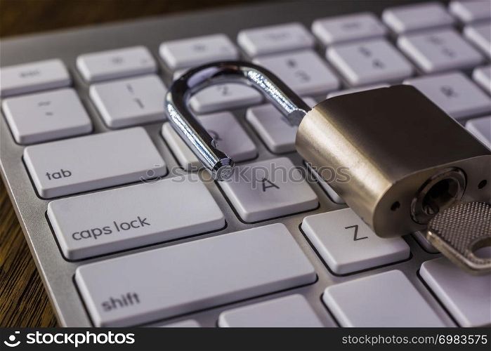 Unlock padlock key on white keyboard with tab, caps lock buttons, dark dim light. Digital data, encryption, cyber security, information privacy, business solution, internet connection concepts.