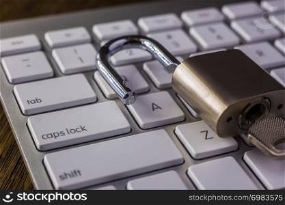 Unlock padlock key on white keyboard with tab, caps lock buttons, dark dim light. Digital data, encryption, cyber security, information privacy, business solution, internet connection concepts.