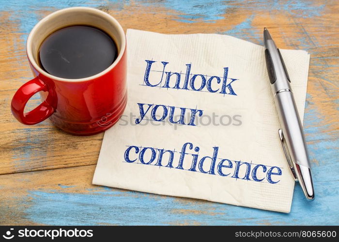 Unlock your confidence advice or reminder - handwriting on a napkin with a cup of espresso coffee