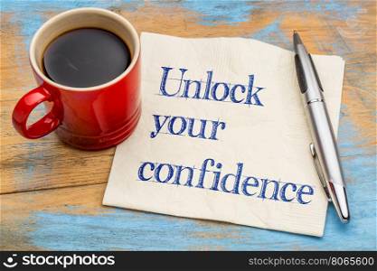 Unlock your confidence advice or reminder - handwriting on a napkin with a cup of espresso coffee