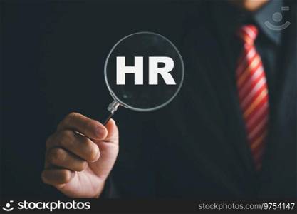 Unlocking HRM potential Magnifier glass highlights manager icon in staff icons, representing power of human resource management in recruitment, leadership, employee development. employees selection