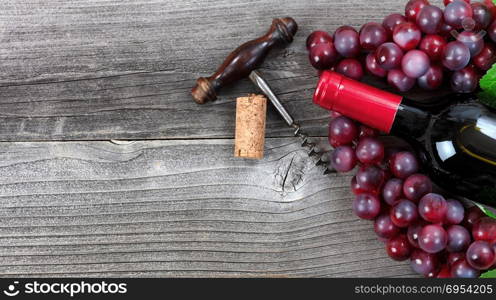 Unopen bottle of red wine and grapes on vintage wood