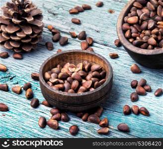 unpeeled cedar nut in mortar. Cedar nuts in a shell in a wooden tub