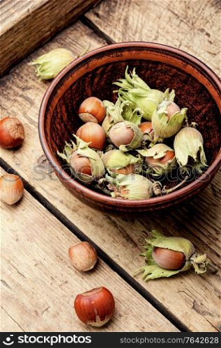 Unpeeled hazelnuts in a bowl on a wooden table. Hazelnuts in the husk