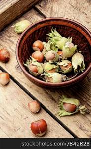 Unpeeled hazelnuts in a bowl on a wooden table. Hazelnuts in the husk