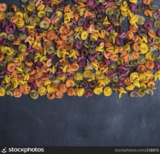 unprepared fusilli pasta multicolored spiral of wheat flour on a black background, copy space