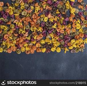 unprepared fusilli pasta multicolored spiral of wheat flour on a black background, copy space
