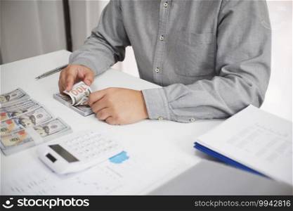 Unrecognisable businessman, accountant, banker counting money at the workplace, white background.
