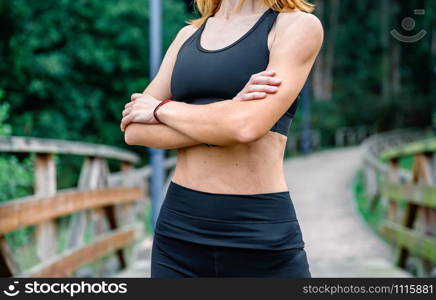 Unrecognizable athlete woman posing with arms crossed outdoors