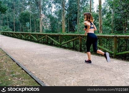 Unrecognizable athlete woman running through a park