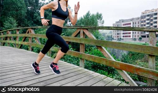 Unrecognizable athlete woman running through an urban park