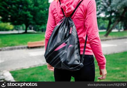Unrecognizable athlete woman with backpack going to the gym outdoors