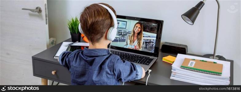 Unrecognizable boy with headphones receiving class at home with laptop from his bedroom. Home schooling concept